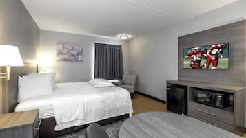 Ein Hotelzimmer mit Bett, Fernseher, Schreibtisch und Stuhl.