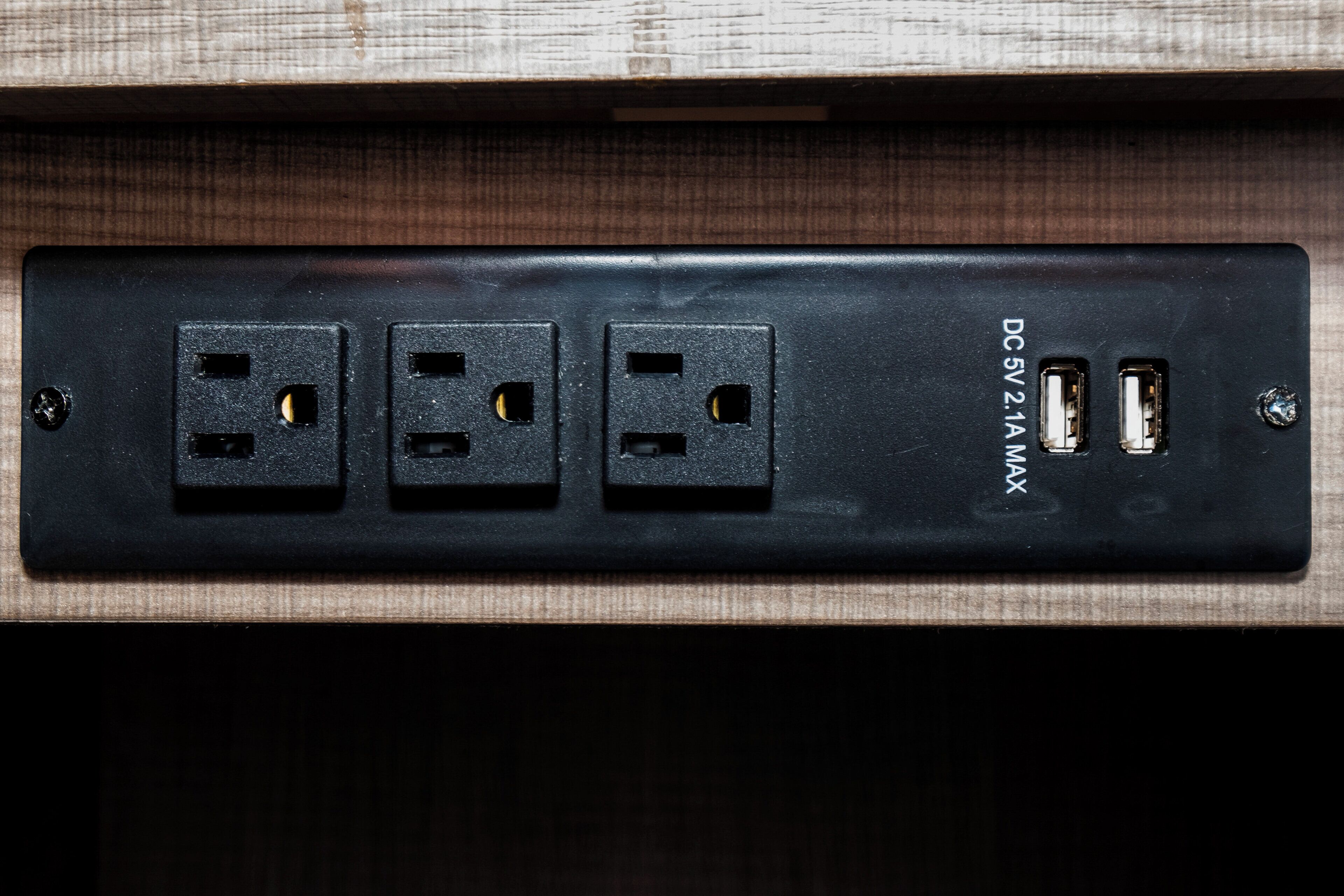 A wall-mounted power strip with three standard electrical outlets and two USB ports.