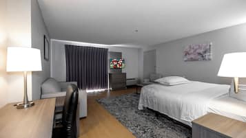 Una habitación de hotel moderna con cama, escritorio, sillón, sofá, televisor y un cuadro en la pared.
