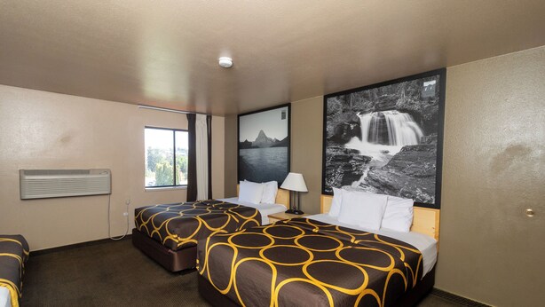 A hotel room with two beds, a window, a wall-mounted air conditioner, and a large waterfall painting. - FairBridge Inn & Suites Moscow/Pullman (Moscow)