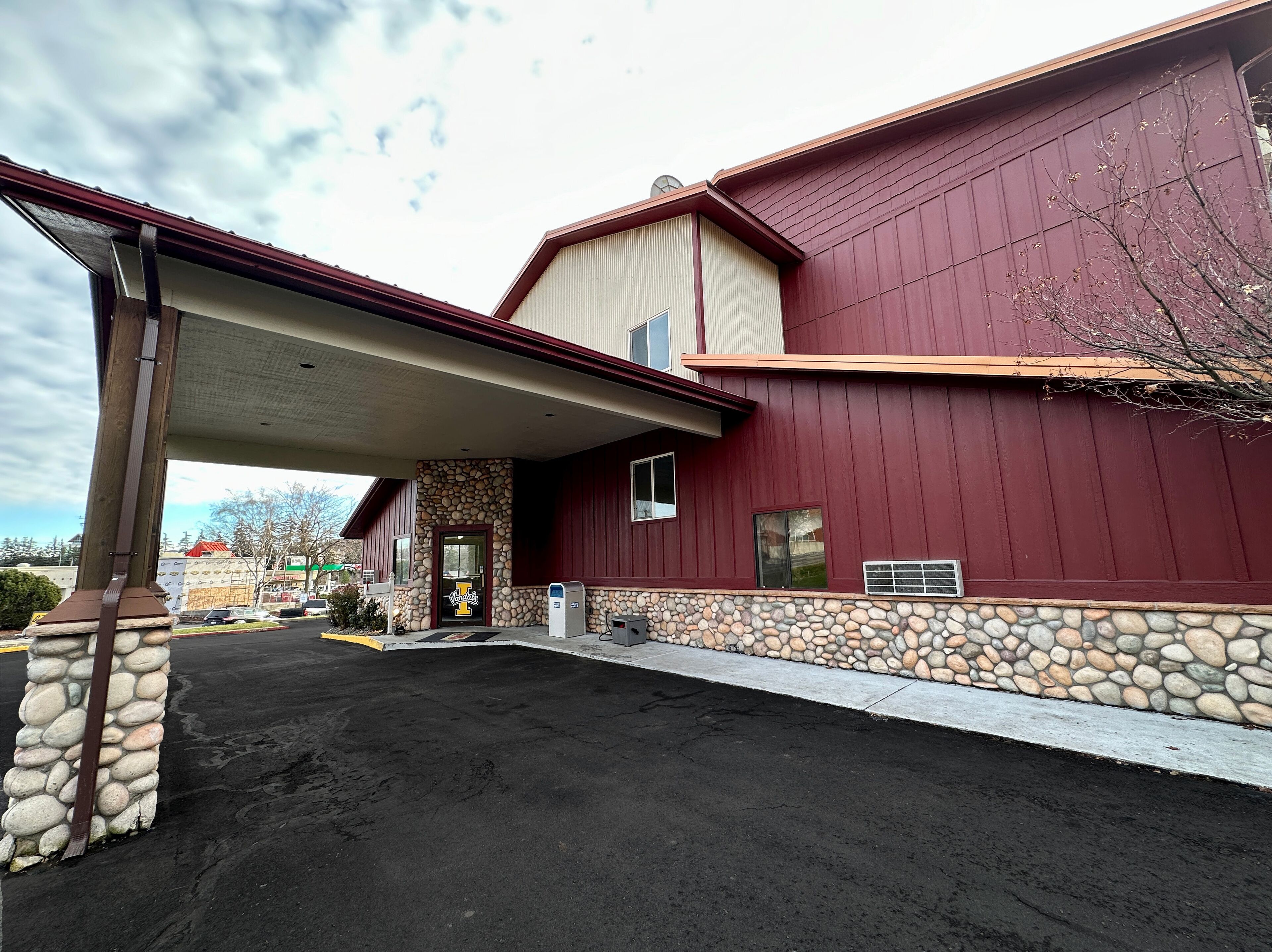 A building with a stone foundation, a red exterior, and a covered entrance.