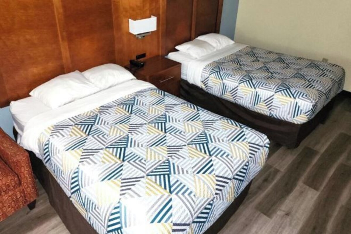 Two single beds with patterned bedding, wooden headboards, and a wooden floor.