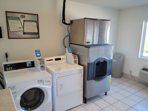 A laundry facility with a front-loading washer, a stacked dryer, and a water dispenser.