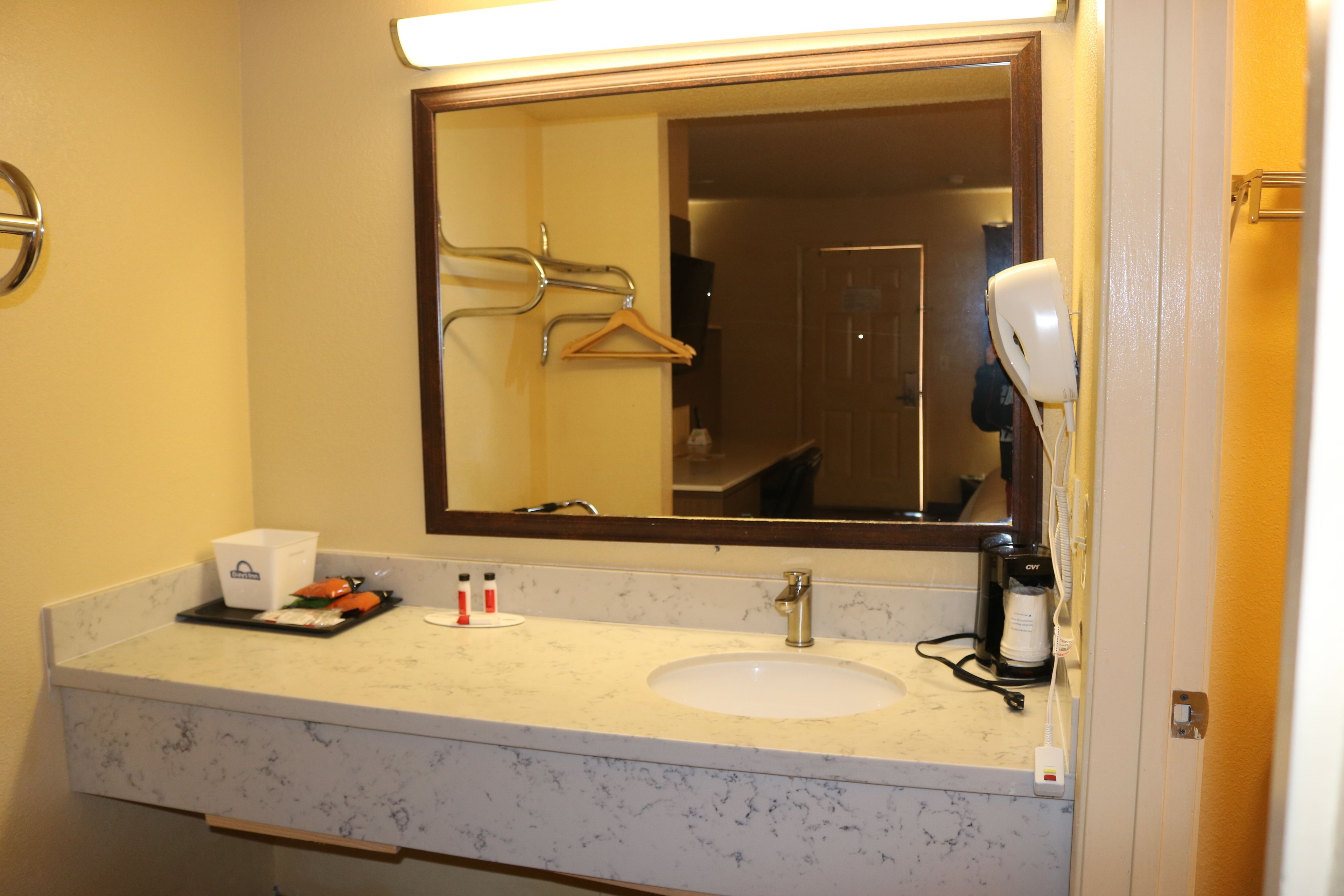 A bathroom with a sink, mirror, towel rack, and a hairdryer.
