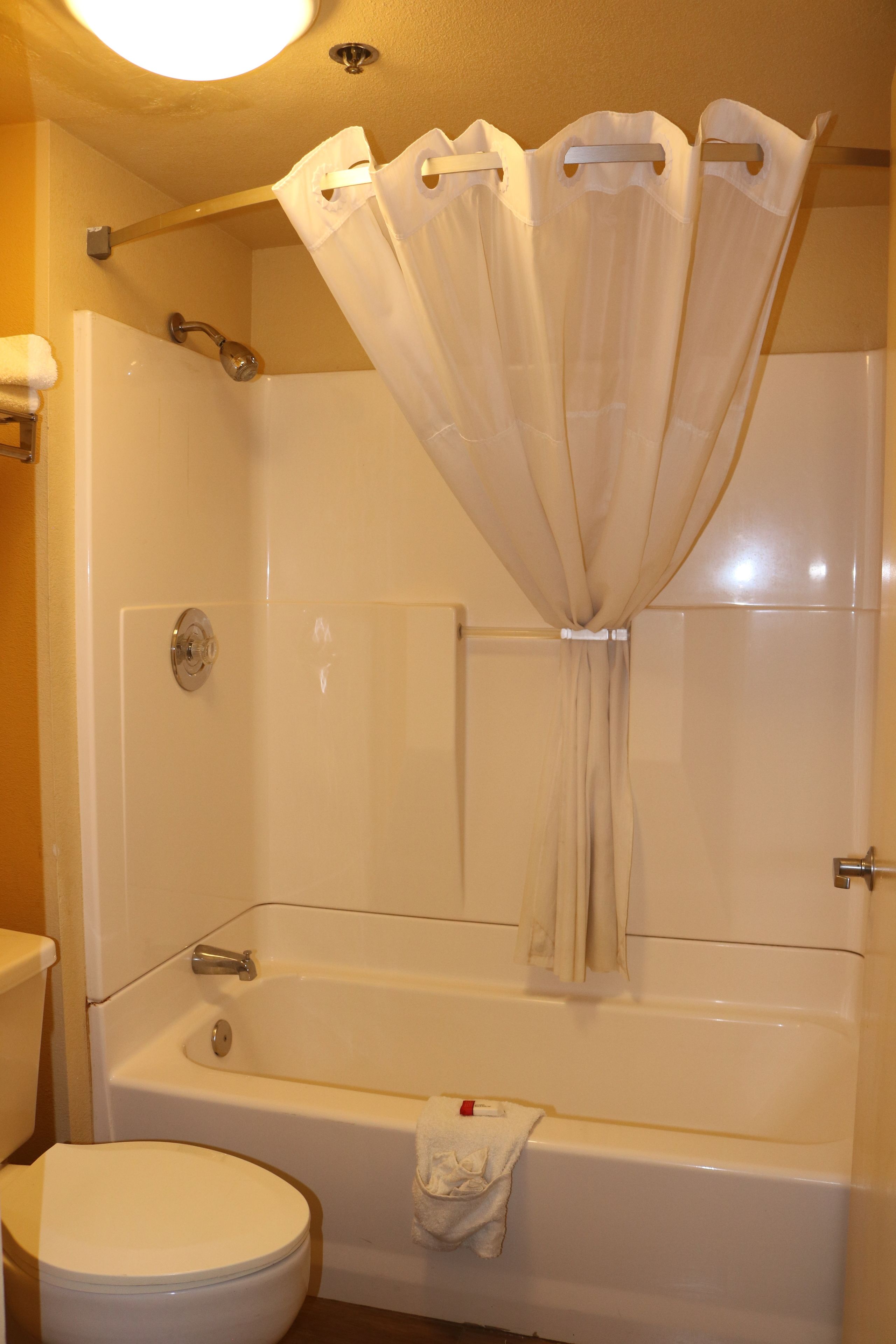 A bathroom with a bathtub, toilet, and shower curtain.