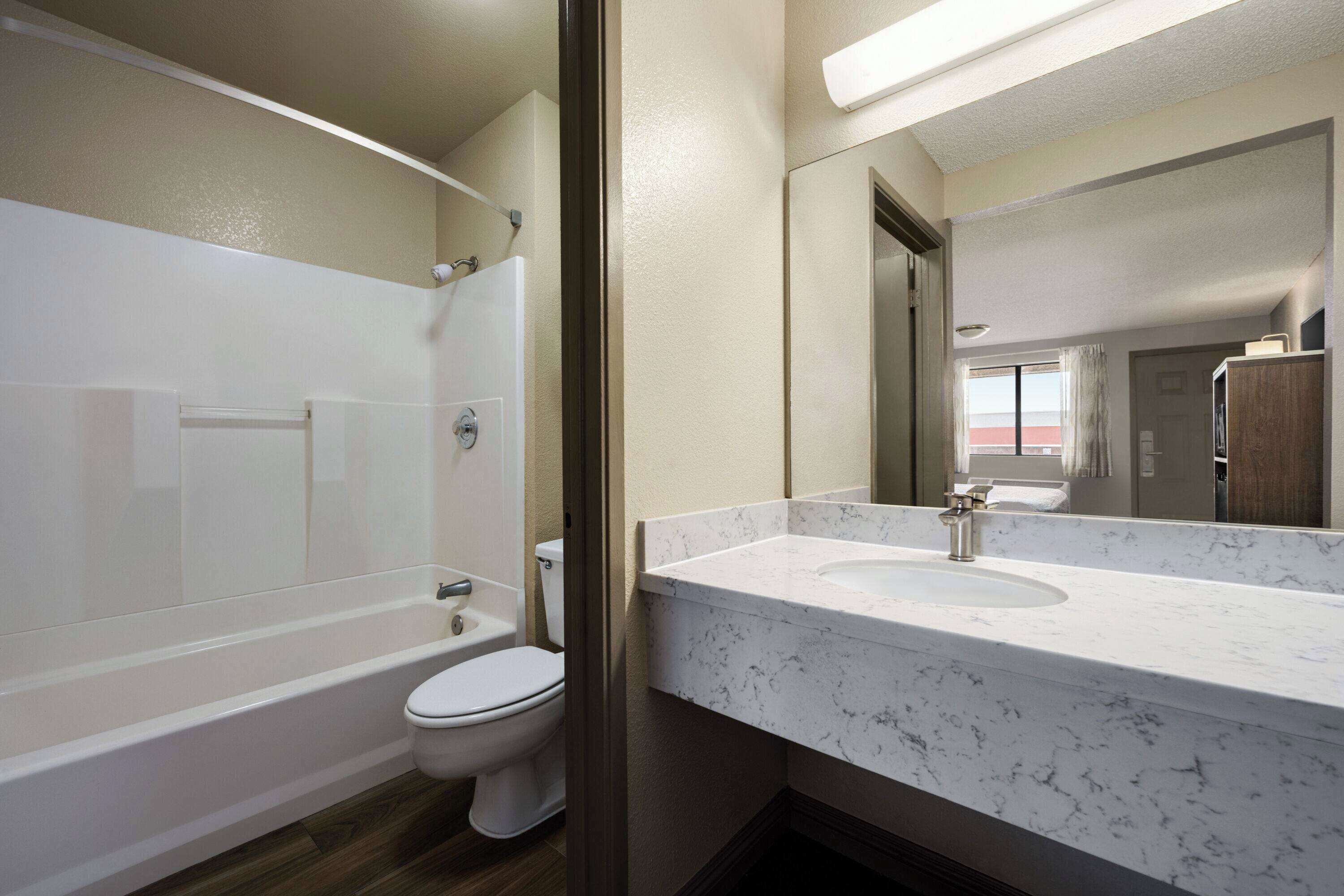 Un baño moderno con bañera, inodoro y lavamanos de mármol.