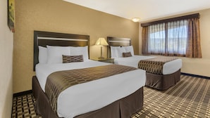 A hotel room with two beds, a window with curtains, a patterned carpet, and a wall-mounted lamp. - Best Western Plus Pleasanton Inn (Pleasanton)