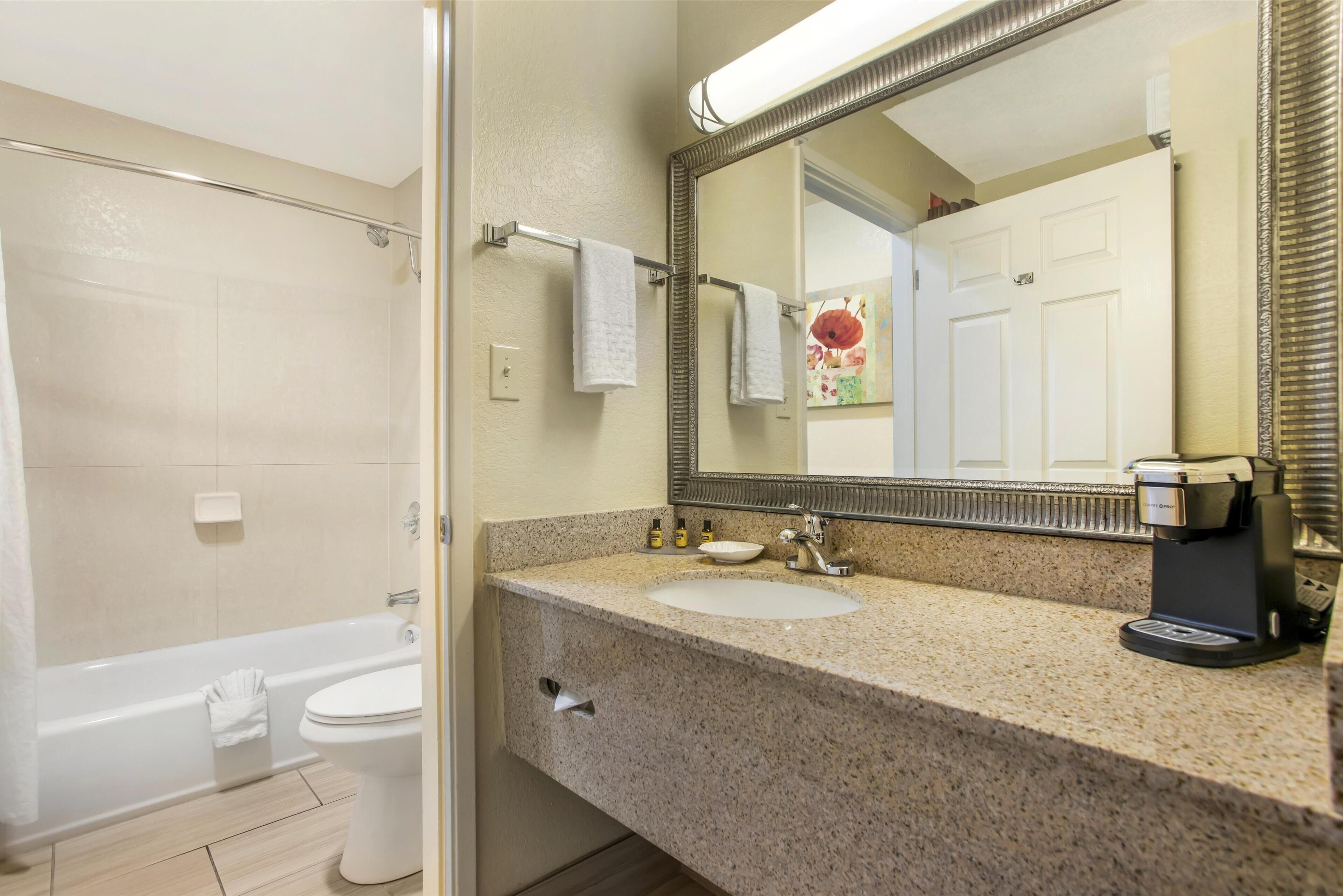 A bathroom with a bathtub, toilet, sink, and coffee maker.