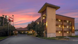 A hotel with a modern design, featuring a prominent entrance, multiple balconies, and a well-lit facade. - Best Western Plus Pleasanton Inn (Pleasanton)