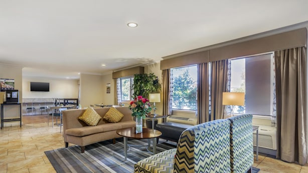 A hotel room with a sofa, armchair, dining table, and a TV. - Best Western Plus Pleasanton Inn (Pleasanton)