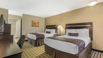 A hotel room with two beds, a desk, a chair, a TV, and a painting on the wall.