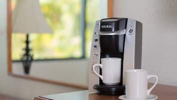 A Keurig coffee machine with a cup and saucer on a wooden table.