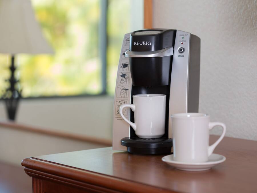 A Keurig coffee machine with a cup and saucer on a wooden table.