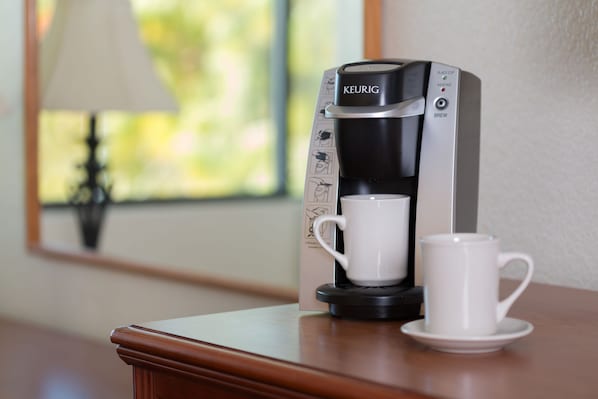 Una cafetera Keurig con una taza y un platillo sobre una mesa de madera.