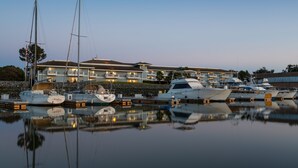 A marina with several yachts docked in front of a multi-story hotel with balconies. - The Marina Inn on San Francisco Bay (San Leandro)