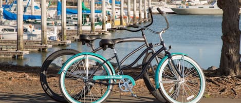 A bicycle parked by a waterfront with boats in the background.