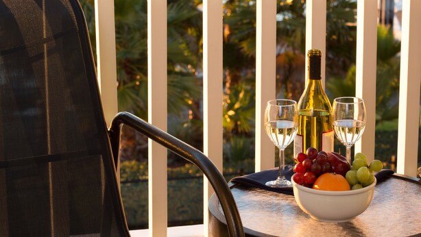 A dining table with a bowl of fruit, a bottle of wine, and two wine glasses. - The Marina Inn on San Francisco Bay (San Leandro)