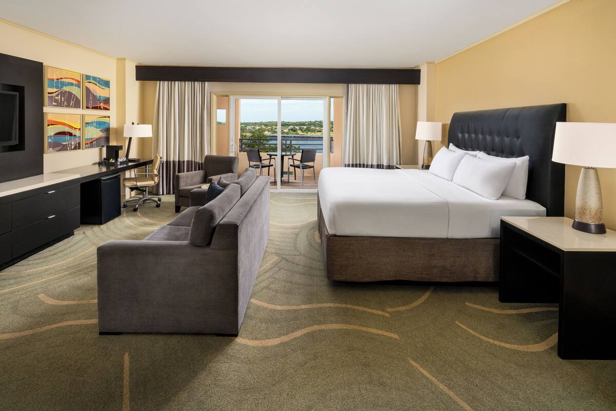 A hotel room with a bed, a sofa, a desk, and a TV.