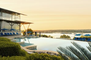 A modern hotel pool area with clear views of a body of water and a distant cityscape. - Lakeway Resort & Spa (Lakeway)