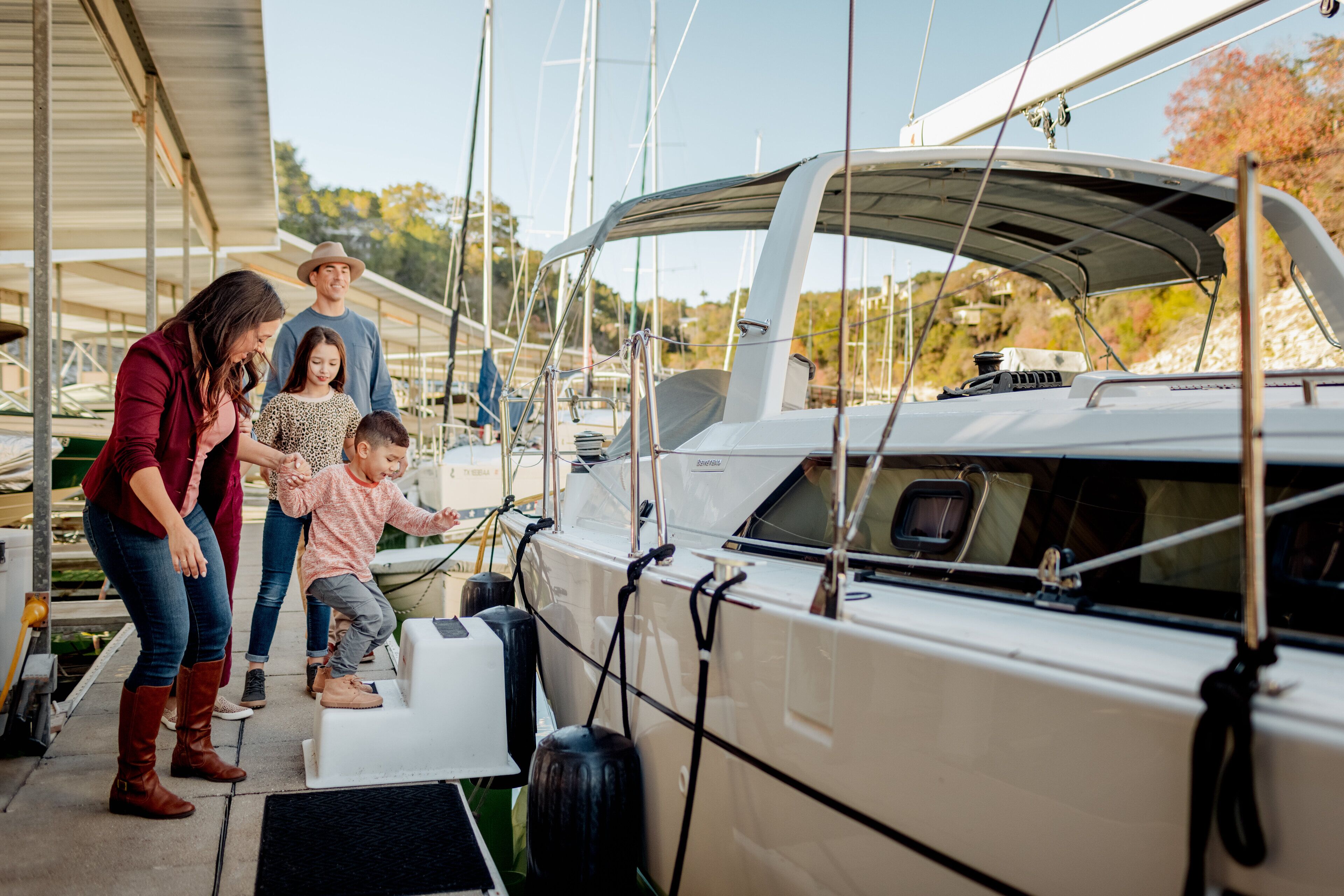 A marina with a white yacht docked, people standing by the boat, and a covered walkway.
