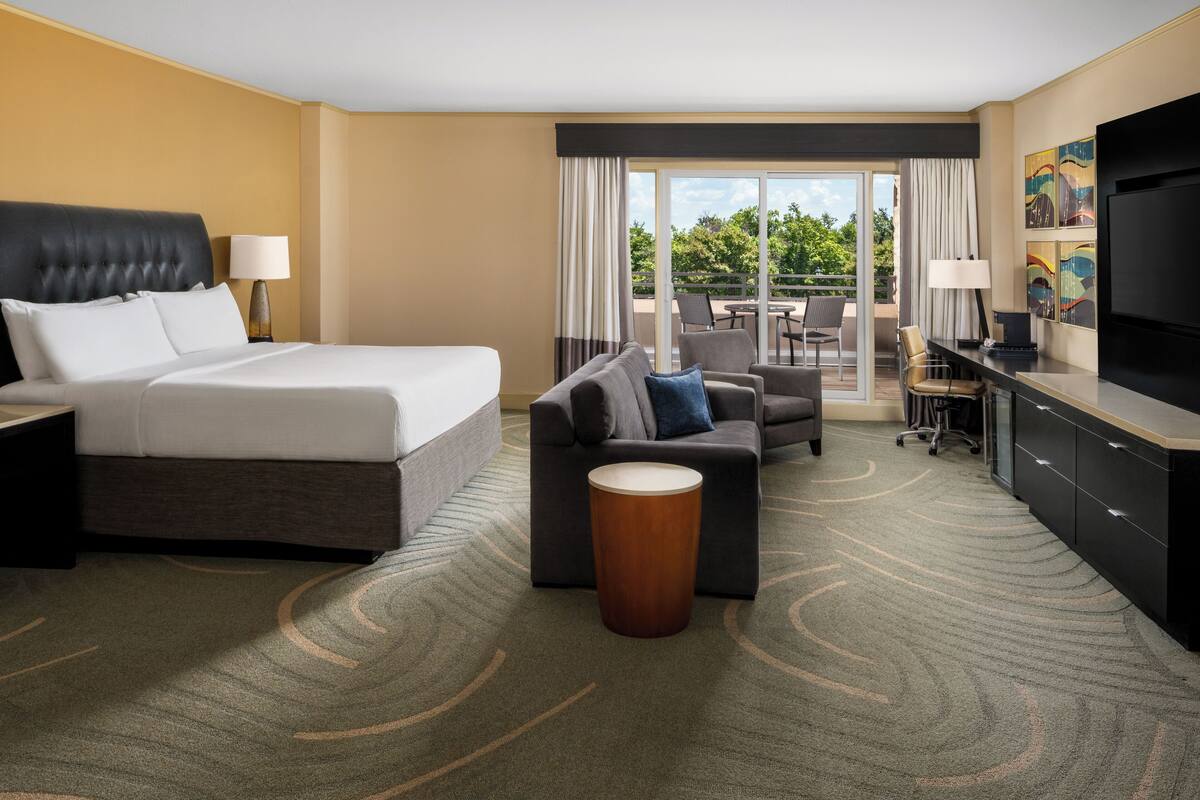A hotel room with a bed, a sofa, a desk, and a TV.