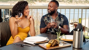 A couple dining at a table with a scenic view of the beach and ocean.
