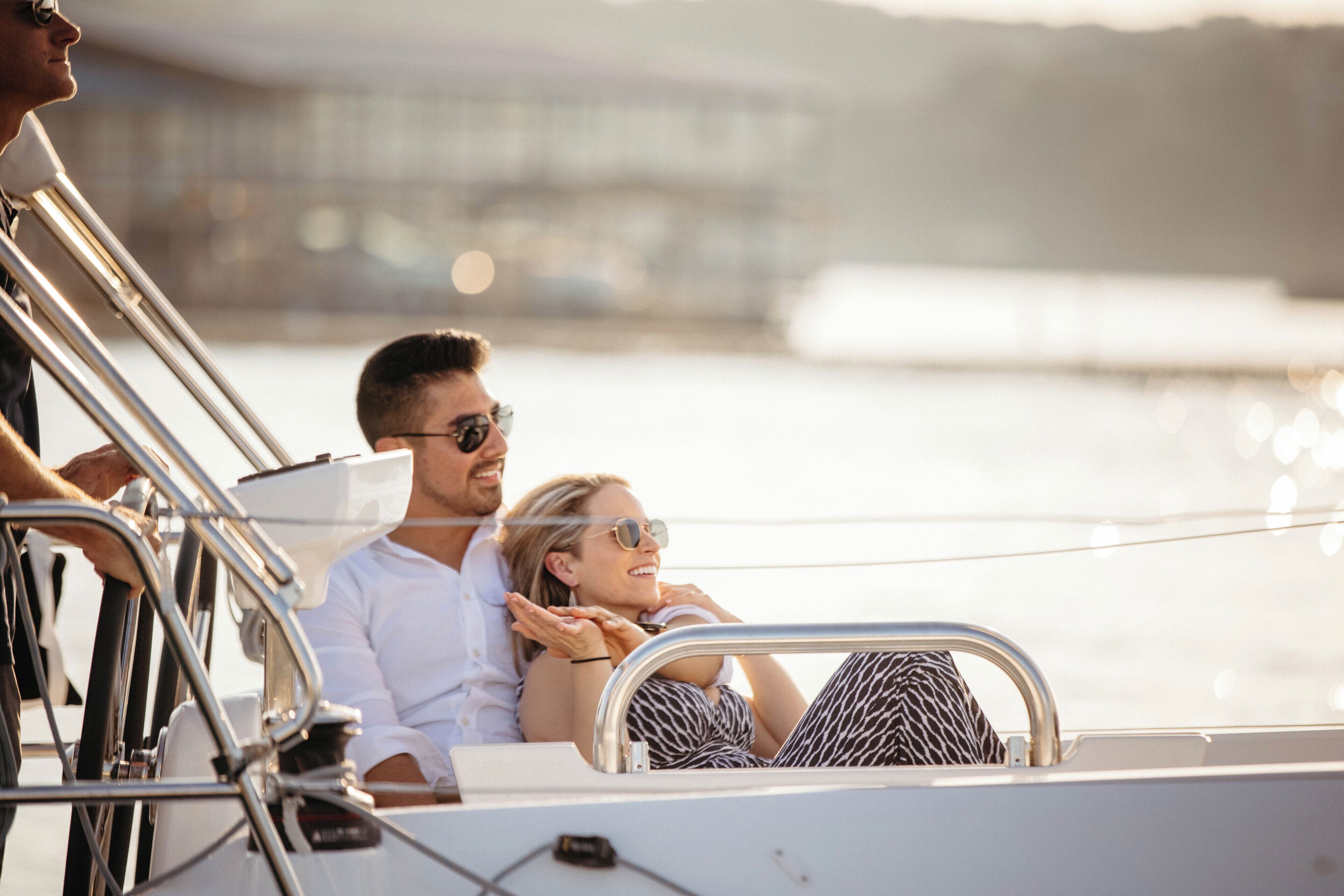 A couple on a boat with metal railings and a view of the water.