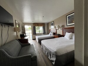 A hotel room with two beds, a sofa, a TV, and a window with curtains. - Fresno Inn (Fresno)