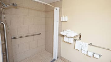 A shower area with a handrail, a white shower curtain, and a towel rack with towels.