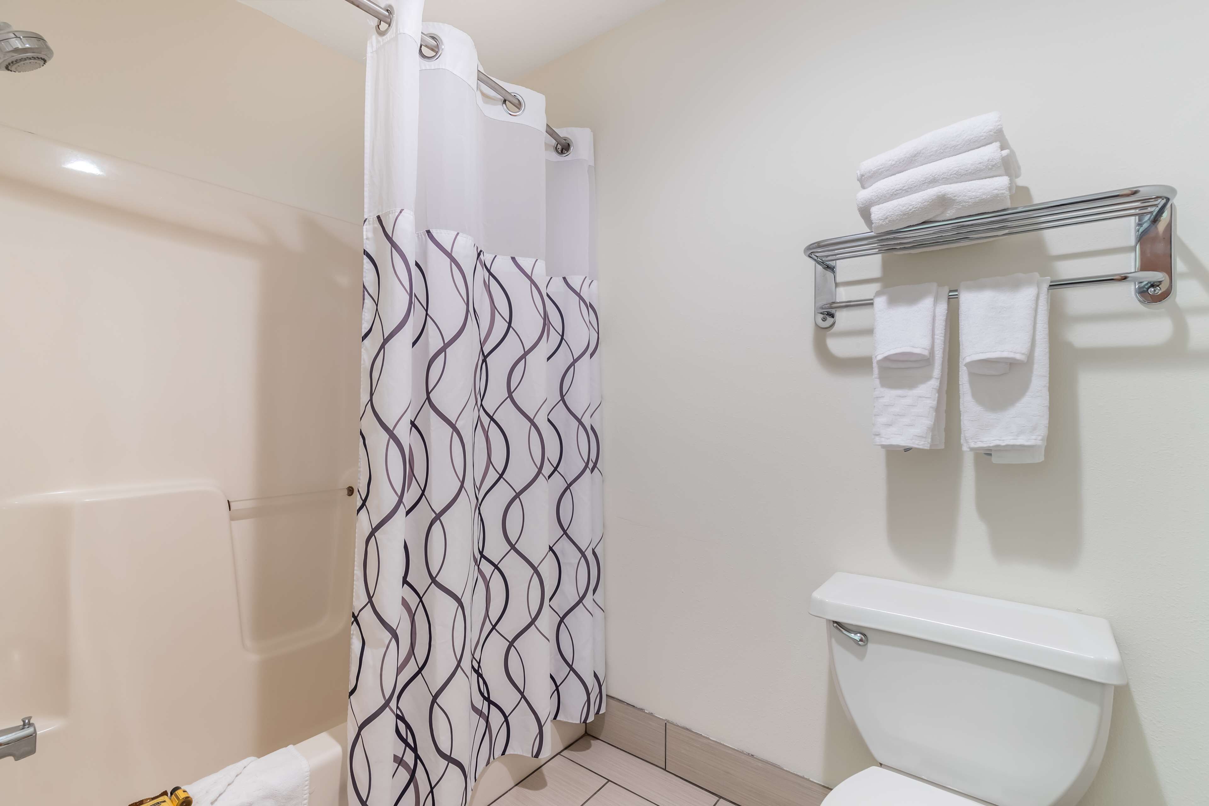 A bathroom with a shower curtain, a toilet, and a towel rack with towels.