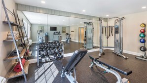 A gym with exercise equipment, a mirror, and a rack of dumbbells.