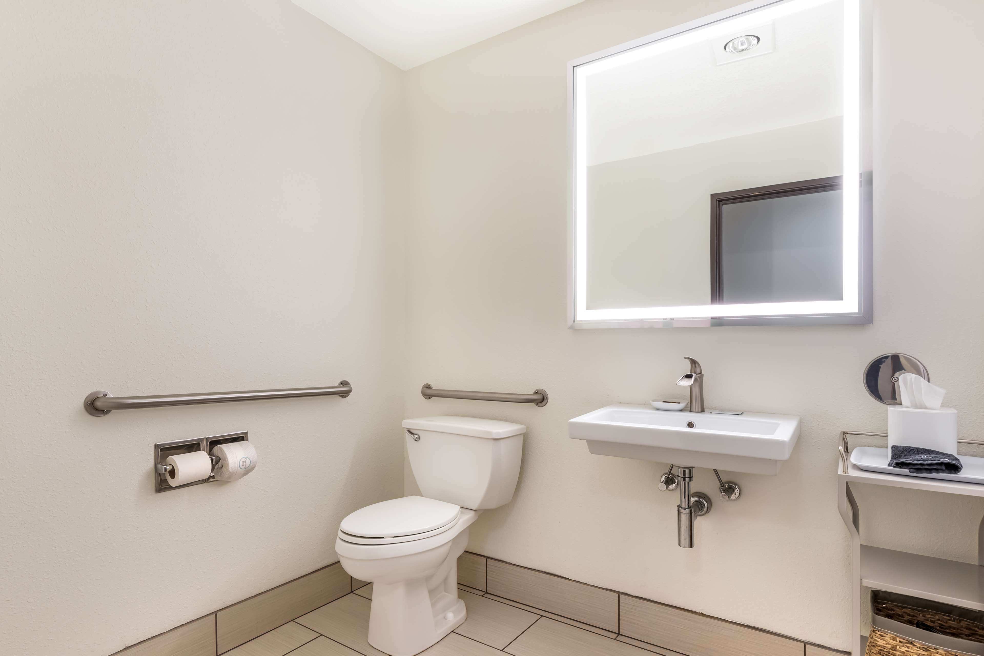 A modern bathroom with a toilet, bidet, sink, and mirror.
