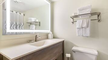 A bathroom with a white sink, a mirror, a towel rack, and a toilet.