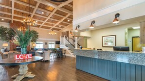 A spacious lobby with a reception desk, a dining area, and a staircase leading to upper floors.
