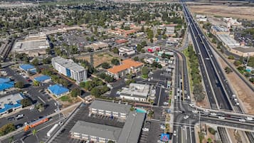 Vue aérienne d’une ville avec un grand parking, un motel et une autoroute.
