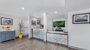 A hotel reception area with a modern design, including a reception desk, a plant, and framed pictures on the walls. - Hillstone Inn Tulare, an Ascend Collection Hotel (Tulare)