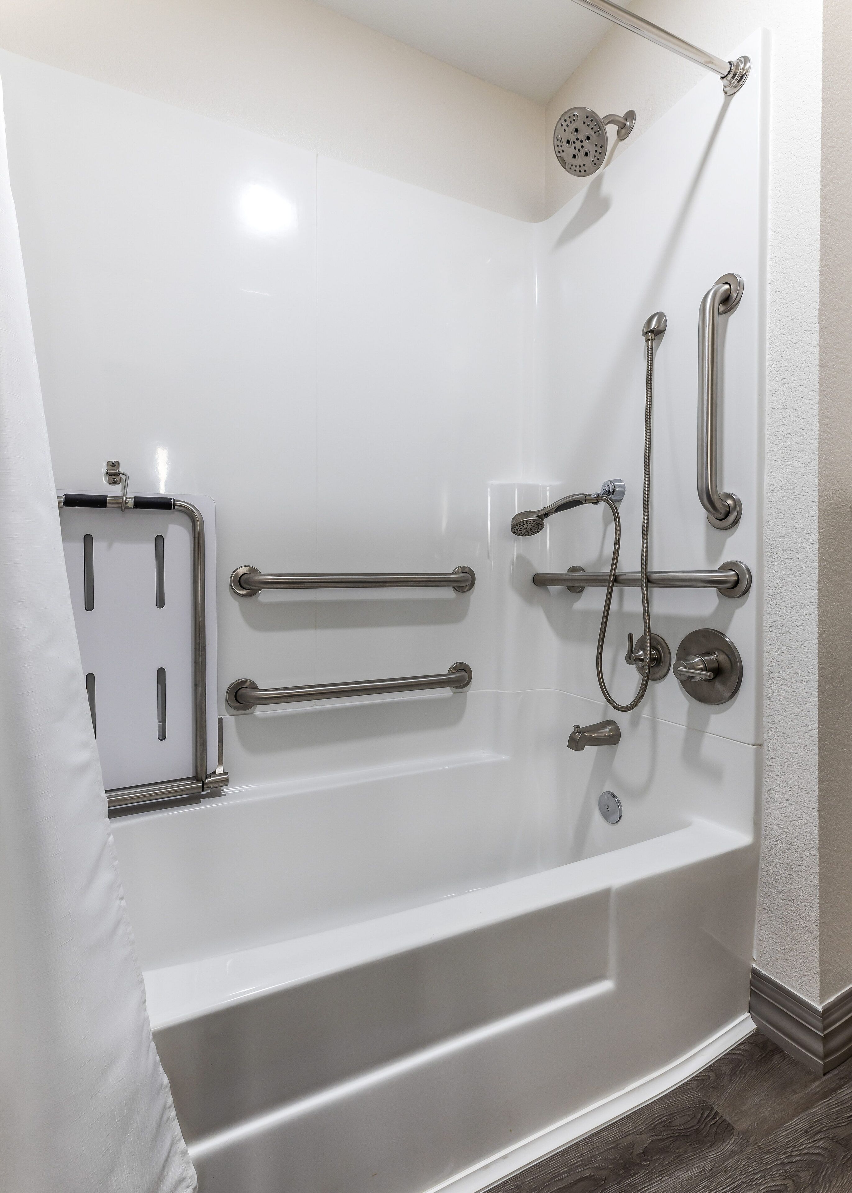 A modern bathroom with a walk-in shower, grab bars, and a handheld showerhead.