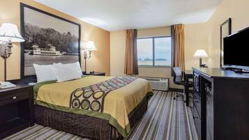 A hotel room with a bed, a desk, a television, and a window with curtains.
