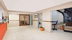A spacious lobby with a reception desk, a seating area with a sofa and armchairs, and a door leading to another room. - Super 8 by Wyndham Iowa Falls (Iowa Falls)