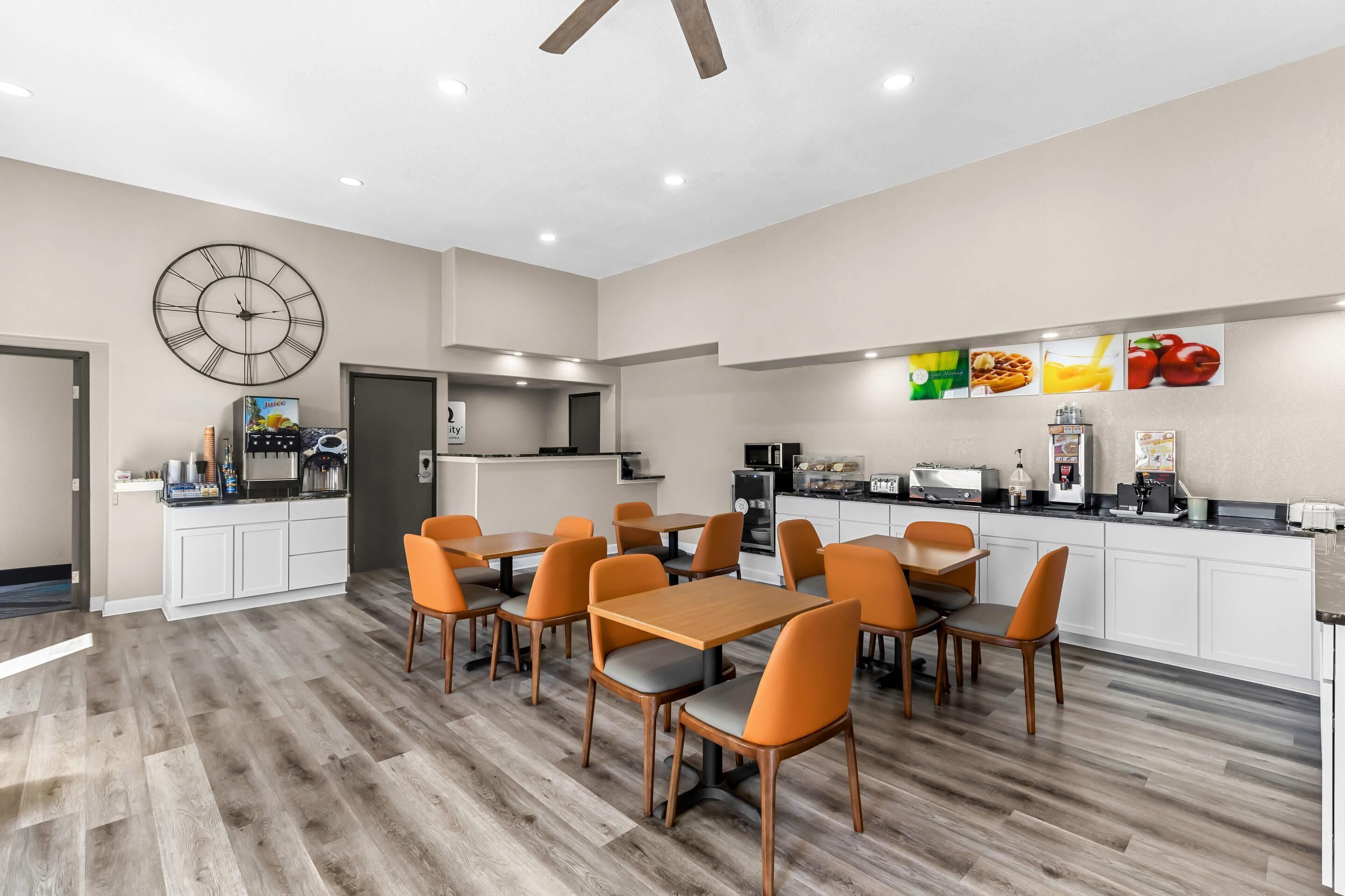 A modern kitchen with white cabinets, a clock, and a fruit display.