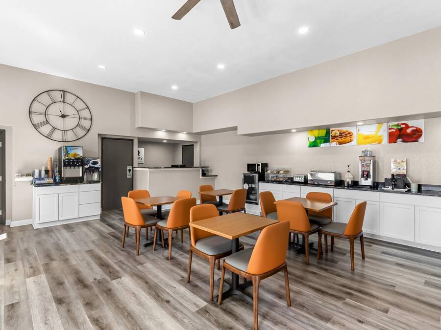 A modern kitchen with white cabinets, a clock, and a fruit display.