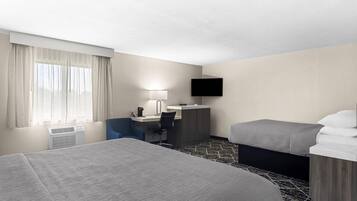 A hotel room with a bed, desk, chair, TV, and a window with curtains.