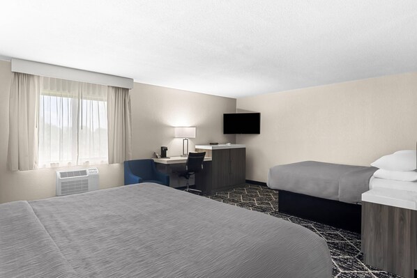 A hotel room with a bed, desk, chair, TV, and a window with curtains.