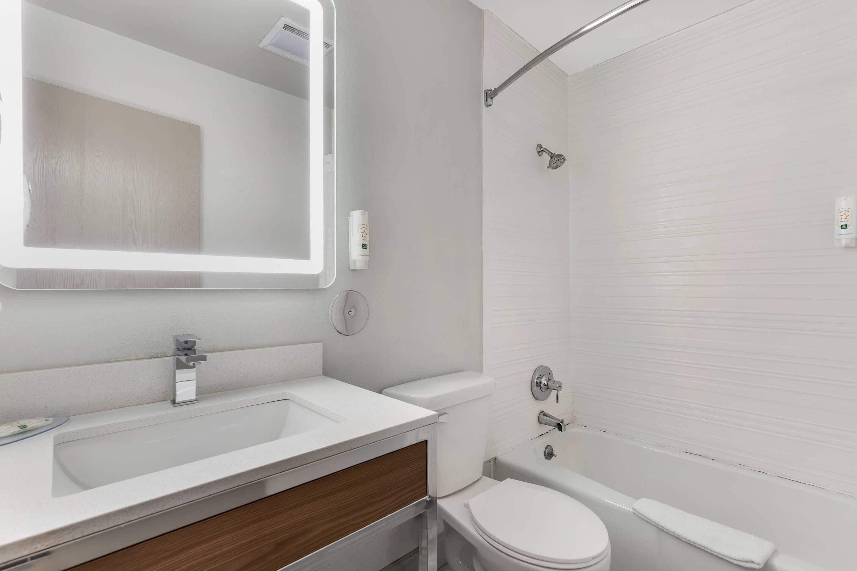Une salle de bain moderne équipée d’un lavabo, d’un miroir, de toilettes et d’une douche.