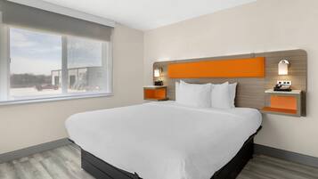 A modern hotel room with a large bed, a window with a view, and two bedside tables with lamps.