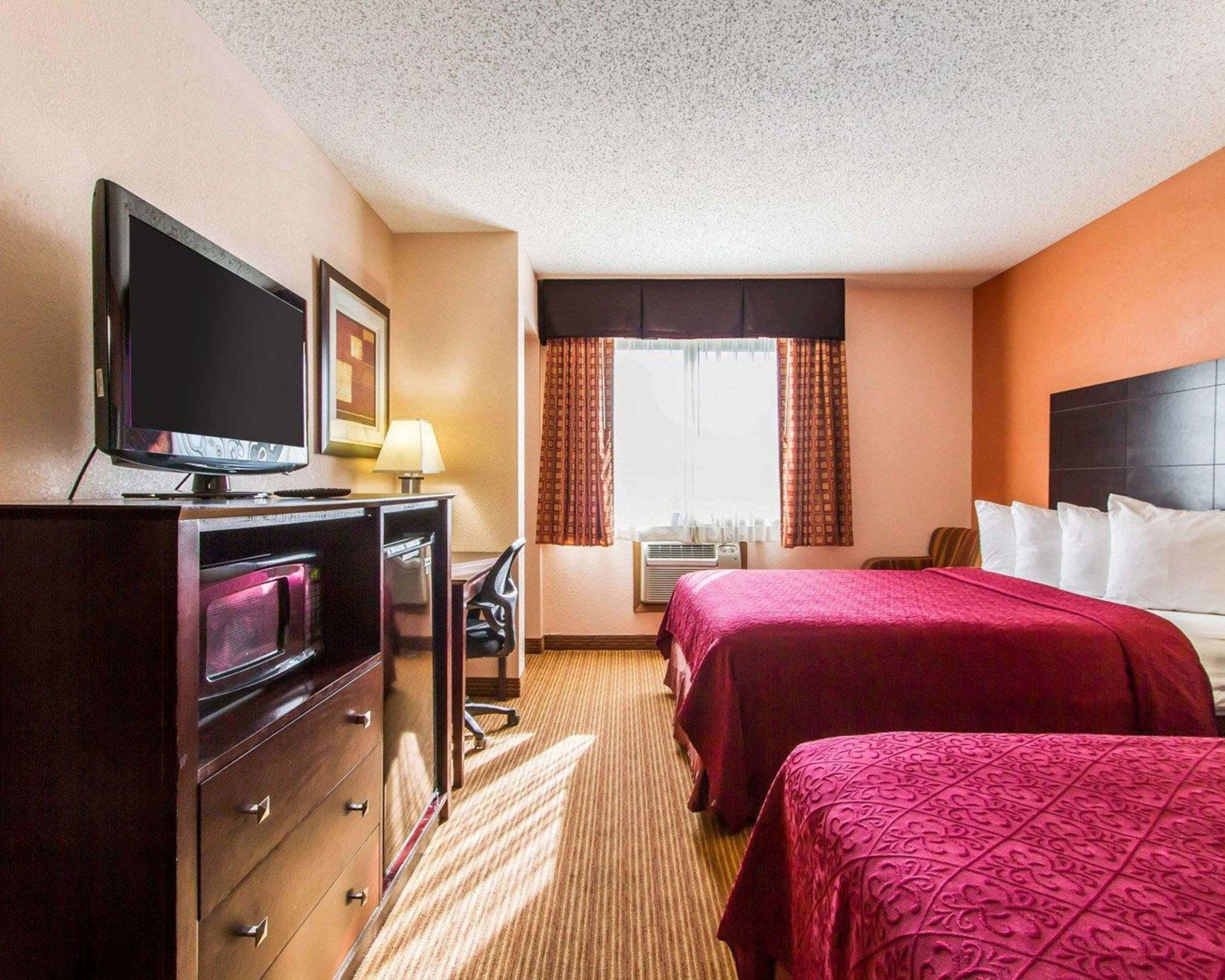 A hotel room with two beds, a desk with a computer, a TV, and a dresser.