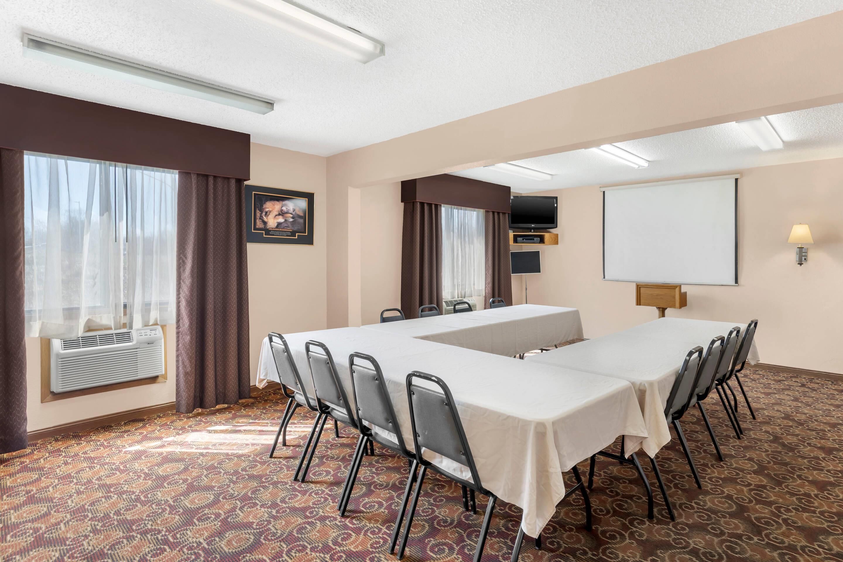 A conference room with a long table, chairs, a projector screen, and a whiteboard.