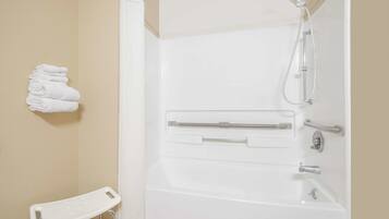 A white bathtub with a showerhead and grab bars, a white towel rack, and a white step stool.