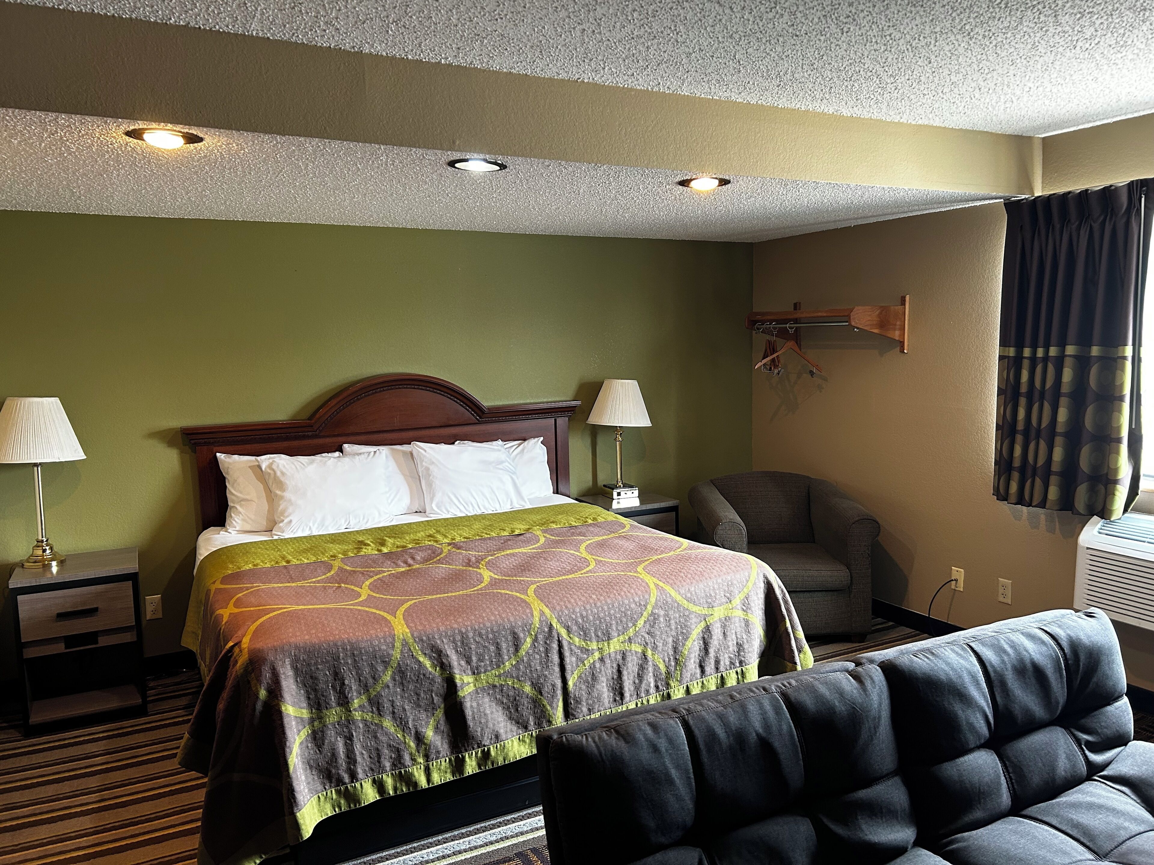 A hotel room with a bed, two bedside lamps, a chair, and a window with curtains.
