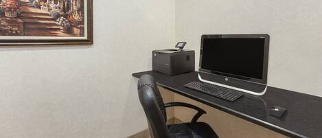 Un espace de travail équipé d’un ordinateur de bureau, d’une imprimante et d’une chaise.